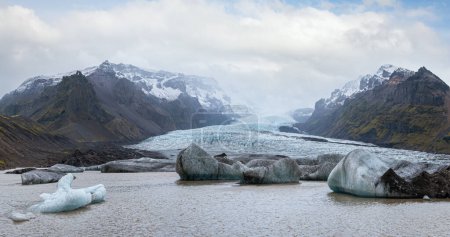 Foto de La lengua glaciar se desliza desde el glaciar Vatnajokull o glaciar Vatna cerca del volcán subglacial Oraefajokull, Islandia. Laguna glaciar con bloques de hielo y montañas circundantes. - Imagen libre de derechos