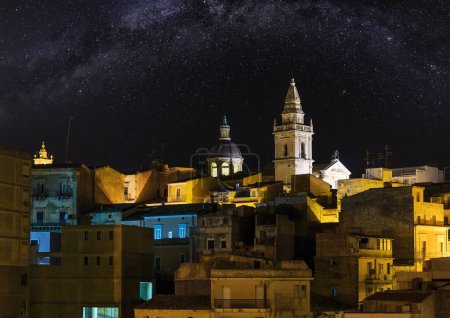 Foto de Noche de edad medieval Ragusa famos Sicilia vista de la ciudad (Sicilia, Italia) con la Vía Láctea en el cielo. Luces de la ciudad de destino turístico famoso. Unesco Patrimonio de la Humanidad. - Imagen libre de derechos