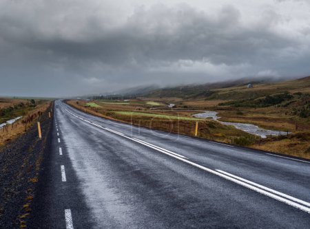 Téléchargez les photos : Route et vue sur la montagne pendant le voyage en auto en Islande. Paysage islandais spectaculaire avec une nature pittoresque : montagnes montagneuses, champs, nuages, glaciers, cascades - en image libre de droit