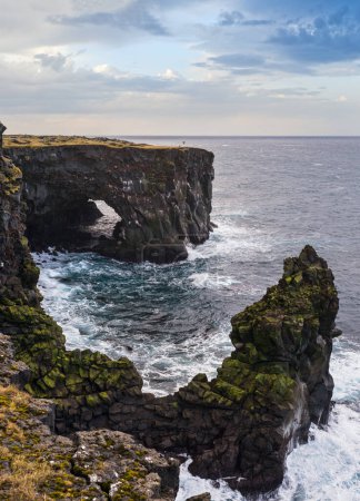 Téléchargez les photos : Vue pendant le voyage en auto dans l'est de l'Islande, la péninsule de Snaefellsnes, View Point près du phare de Svortuloft. Spectaculaire côte volcanique noire de l'océan rocheux avec arche de grotte et tours. - en image libre de droit