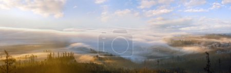 Photo for Clouds illuminated by the morning sun floating low over the valley. Country panorama view from Slowakian High Tatras. - Royalty Free Image