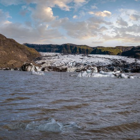 Téléchargez les photos : Solheimajokull glacier pittoresque dans le sud de l'Islande. La langue de ce glacier glisse du volcan Katla. Beau lagon lacustre glaciaire avec blocs de glace et montagnes environnantes. - en image libre de droit