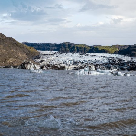 Foto de Solheimajokull pintoresco glaciar en el sur de Islandia. La lengua de este glaciar se desliza desde el volcán Katla. Hermosa laguna glacial con bloques de hielo y montañas circundantes. - Imagen libre de derechos