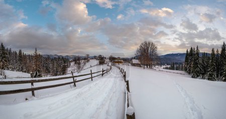 Foto de Camino alpino de campo secundario en pueblo remoto de montaña, deriva de nieve y valla de madera en el camino - Imagen libre de derechos