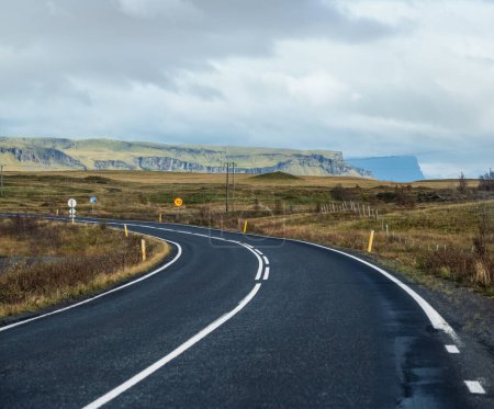 Téléchargez les photos : Route et vue sur la montagne pendant le voyage en auto en Islande. Paysage islandais spectaculaire avec une nature pittoresque : fjords, champs, nuages, glaciers, cascades. - en image libre de droit
