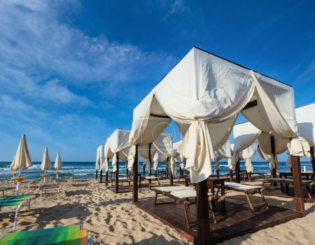 Photo for Luxury beach tents canopies on morning paradise white sandy beach Maldives of Salento (Pescoluse, Salento, Puglia, south Italy). The most beautiful sea sandy beach of Apulia. - Royalty Free Image
