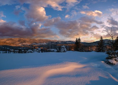 Téléchargez les photos : Aux abords du village alpin au coucher du soleil hier soir. Hiver collines enneigées et sapins. Nuages pittoresques et Lune au crépuscule. - en image libre de droit