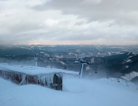 Foto de Remonte alpino con asientos que recorren las pistas de esquí de montaña al atardecer con un clima extremadamente ventoso - Imagen libre de derechos
