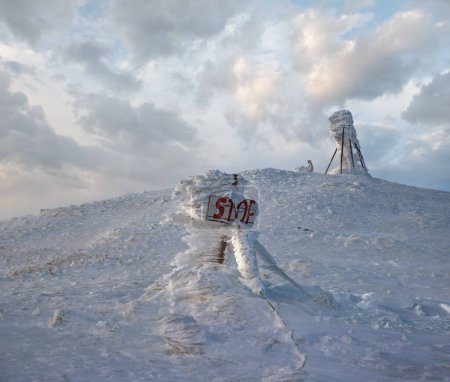 Téléchargez les photos : La neige a couvert le sommet de la montagne d'hiver hier soir avant la tempête de neige. Froid venteux sur les pointeurs et les panneaux d'arrêt sur le précipice dangereux. - en image libre de droit