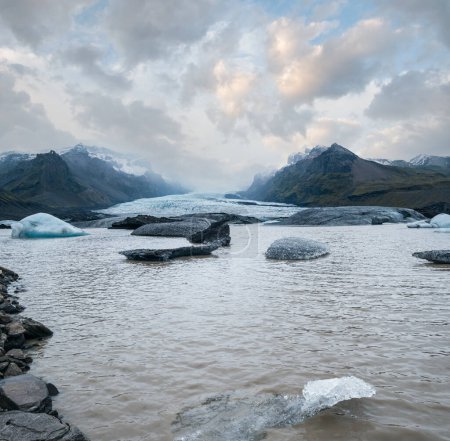 Téléchargez les photos : La langue des glaciers glisse depuis la calotte glaciaire de Vatnajokull ou le glacier de Vatna près du volcan sous-glaciaire Oraefajokull, en Islande. Lagune glaciaire avec blocs de glace et montagnes environnantes. - en image libre de droit