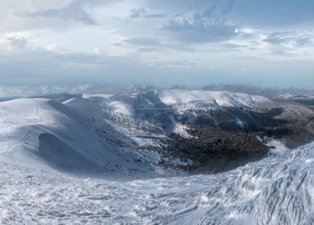 Foto de La nieve y el viento formaron formaciones de hielo que cubrían la meseta montañosa invernal, con cornisas de nieve en gran medida. Magnífico día soleado en la pintoresca cresta alpina hermosa. - Imagen libre de derechos
