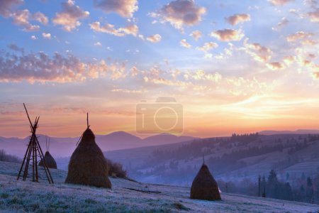 Foto de Primeras heladas de otoño en los pastos con pajar y majestuoso amanecer en el pueblo de las montañas
. - Imagen libre de derechos