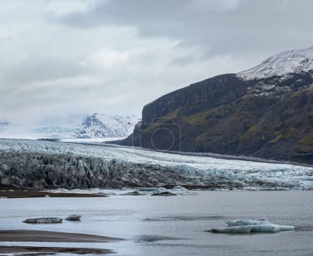 Photo for Skaftafellsjokull glacier, Iceland. Glacier tongue slides from the Vatnajokull icecap or Vatna Glacier near subglacial Esjufjoll volcano. Glacial lagoon with blocks of ice and surrounding mountains. - Royalty Free Image
