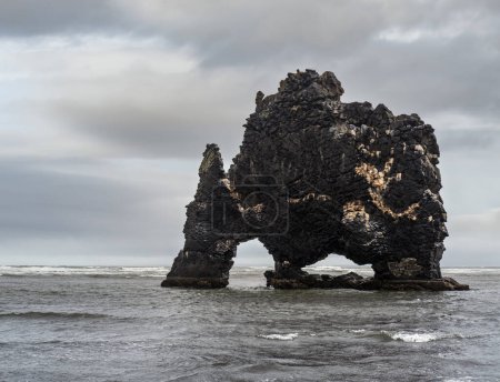 Foto de El elefante bebedor o rinoceronte, pila de basalto Hvitserkur a lo largo de la orilla oriental de la península de Vatnsnes, en el noroeste de Islandia. Impresionante estructura de roca hecha de basalto y de pie 15 metros de altura. - Imagen libre de derechos