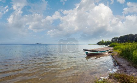 Photo for Old wooden fishing boat near the lake shore and summer sky behind (Svityaz, Ukraine) - Royalty Free Image
