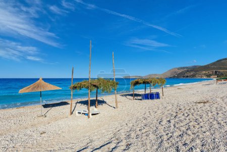 Foto de Mañana de verano playa de guijarros con tumbonas y dosel (Borsh, Albania
). - Imagen libre de derechos