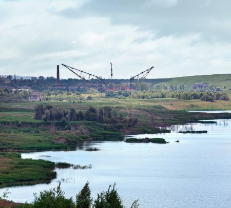 Summer rushy lake view with lifting cranes on opposite shore (destroyed sulfur obtaining plant )