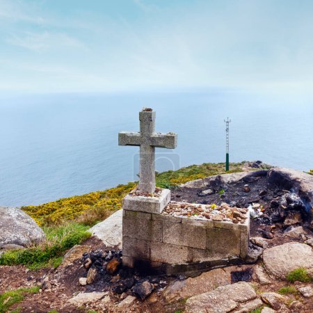 Kreuz und Kamin (wo die Reisenden traditionell am Ende des Weges einen Teil ihrer Kleidung verbrannten und Wünsche hinterließen) auf dem Kap Fisterra (Galicien, Spanien). Sommernebel.