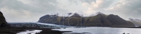 Skaftafellsjokull glacier, Iceland. Glacier tongue slides from the Vatnajokull icecap or Vatna Glacier near subglacial Esjufjoll volcano. Glacial lagoon with blocks of ice and surrounding mountains.