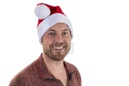 Téléchargez les photos : Portrait d'un jeune homme aux cheveux faciaux portant un chapeau de Père Noël sur fond blanc - en image libre de droit