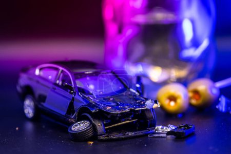 concept image created with a toy car smashed and placed with a drink and olives in the background with red and blur lights