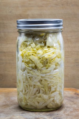 Téléchargez les photos : Home made fermented cabbage in a wide mouth jar on a wooden background - en image libre de droit