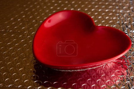 Téléchargez les photos : Close up of a red plate in the shape of a heart on shiny bubble wrap - en image libre de droit