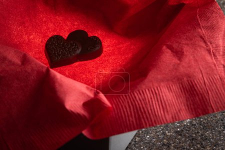 Photo for Heart shaped chocolates in a box with a light inside for a glow and a red napkin for color - Royalty Free Image