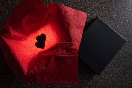 Foto de Heart shaped chocolates in a box with a light inside for a glow and a red napkin for color - Imagen libre de derechos