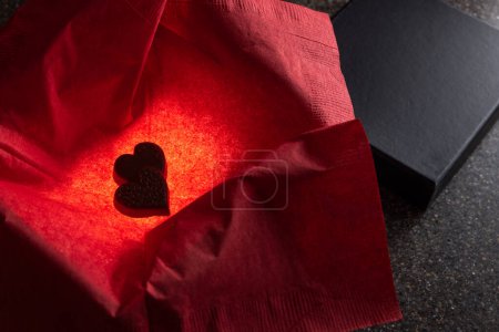 Téléchargez les photos : Heart shaped chocolates in a box with a light inside for a glow and a red napkin for color - en image libre de droit