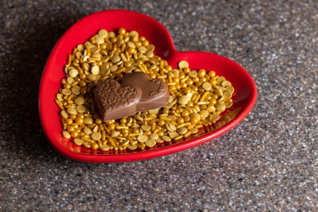 Téléchargez les photos : Heart shaped plate with golden sprinkles and heart shaped chocolates - en image libre de droit
