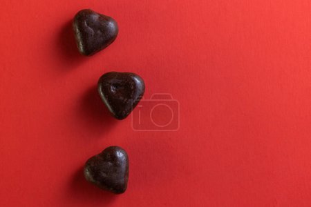 Photo for Heart shaped dark chocolates on a red background for holidays - Royalty Free Image