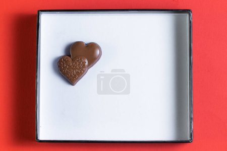 Photo for Heart shaped ring with chocolates inside of a white lid with red all around - Royalty Free Image