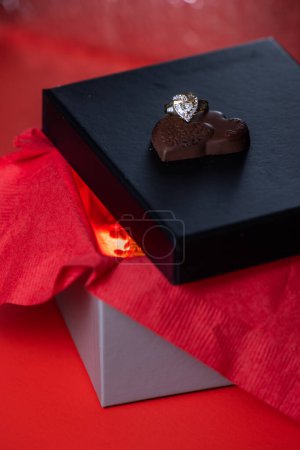 Photo for Heart shaped ring with chocolates on a black box lid - Royalty Free Image