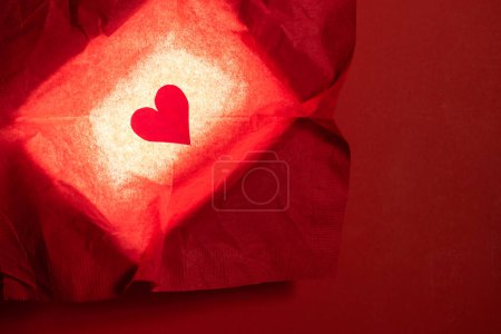 Foto de Close up of a hand cut heart made from paper inside of a red box with a back light for effect - Imagen libre de derechos