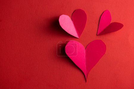 Photo for Hand cut hearts out of red paper on a red background - Royalty Free Image
