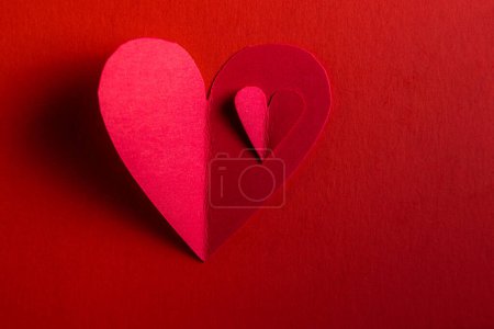 Foto de Hand cut hearts out of red paper on a red background - Imagen libre de derechos
