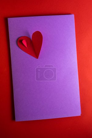 Téléchargez les photos : Concept, for a love note with hand cut hearts photographed on a red background - en image libre de droit