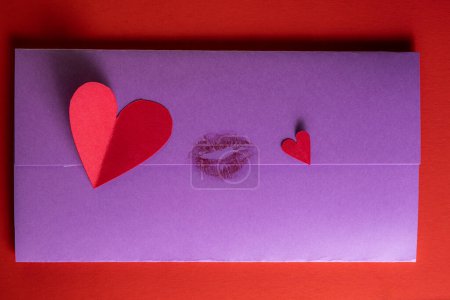 Photo for Concept for a love note with hand cut hearts and a kiss photographed on a red background - Royalty Free Image