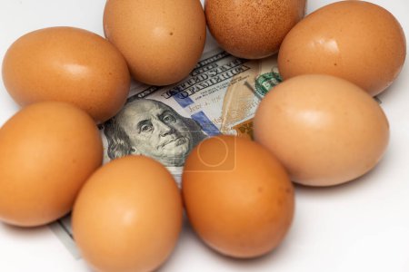 Foto de Fresh eggs on top of a 100 dollar US bill on a white background - Imagen libre de derechos