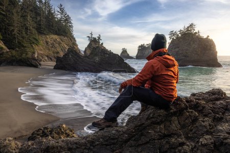 Photo for Man sitting on a rock enjoying the amazing view of the sea and sea stacks in this beautiful spot on the Oregon coast - Royalty Free Image