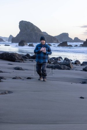 Téléchargez les photos : Homme dans la trentaine ayant des douleurs thoraciques tout en marchant sur la plage - en image libre de droit