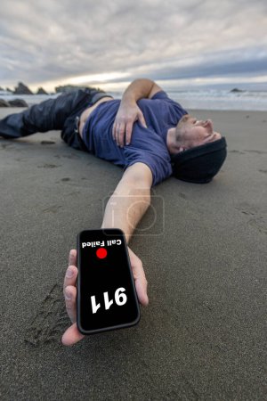 Photo for Man trying to call 911 after collapsing on the beach and holding his chest and showing signs of pain - Royalty Free Image