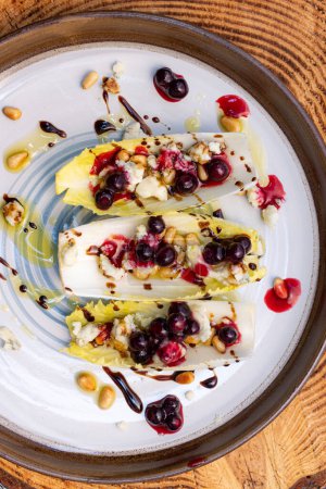 Photo for Vegetarians appetizer made with fresh Belgium endive boats stuffed with toasted pine nuts, bleu cheese, fresh huckleberries and fresh olive oil topped with a balsamic drizzle. - Royalty Free Image