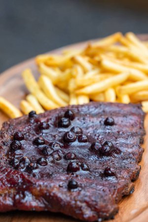 Téléchargez les photos : Côtes de porc fumées fraîches servies avec une sauce barbecue aux airelles et un côté de frites sur un décor rustique - en image libre de droit