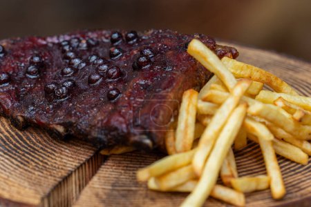 Photo for Fresh smoked pork ribs served with a huckleberry bbq sauce and a side of fries on a rustic setting - Royalty Free Image