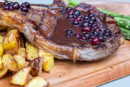 Photo for Grilled bone in ribeye served with potatoes and asparragus topped with a fresh huckleberry port reduction - Royalty Free Image