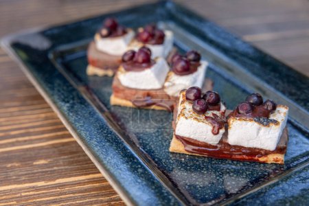 Photo for Delicious huckleberry beef stores with toasted marshmallows with melted chocolate and a huckleberry sauce served outdoors - Royalty Free Image