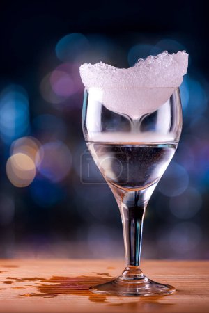 Téléchargez les photos : Gros plan d'un verre transparent recouvert de glace avec une boisson alcoolisée flamboyante créant un brouillard provenant des différentes températures - en image libre de droit