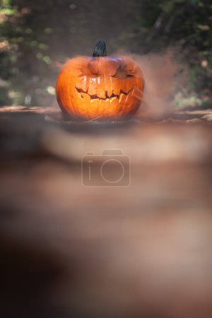 Foto de Primer plano de una calabaza tallada para Halloween con humo saliendo de los recortes en un entorno de bosque espeluznante natural - Imagen libre de derechos